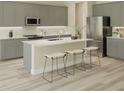 Modern kitchen with gray cabinetry, stainless steel appliances, a center island with seating, and light wood flooring at 6229 Sw 96Th Pl, Ocala, FL 34476