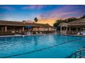 Large community pool with comfortable lounge chairs under blue umbrellas, under a beautiful evening sky at 6237 Sw 96Th Pl, Ocala, FL 34476