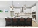 Modern kitchen featuring a large island, white cabinets, stainless steel appliances, and stylish pendant lighting at 5950 Bristle Oak St, Mount Dora, FL 32757