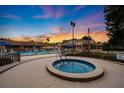 Community pool with a spa, sun loungers, and a covered pavilion set against a vibrant sunset sky at 6214 Sw 96Th Pl, Ocala, FL 34476