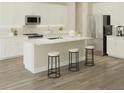Modern kitchen featuring white cabinets, stainless steel appliances, an island with bar seating, and hardwood floors at 6237 Sw 97Th St, Ocala, FL 34476