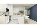 Modern white kitchen with stainless steel appliances, an island, and bar stool seating at 2798 Pioneer Trl, Eagle Lake, FL 33839