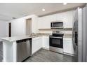 Bright kitchen with stainless steel appliances, granite countertops, and gray wood flooring at 3817 Corsican Pl, Lake Alfred, FL 33850