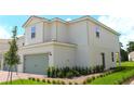 Exterior of a two-story home featuring a two-car garage, well-maintained lawn and landscaping at 616 Bay Leaf Dr, Poinciana, FL 34759