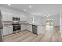 Open kitchen with stainless appliances, granite counters, and wood-look flooring at 385 Begonia Ct, Poinciana, FL 34759