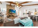 Open-concept living room boasts vaulted ceilings with wood beams, a brick fireplace, and seamless flow to the modern kitchen at 132 Margate Mews, Longwood, FL 32779
