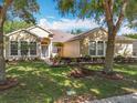 Charming single-story home with a well-manicured lawn, mature trees, and beautiful landscaping at 2376 Home Again Rd, Apopka, FL 32712