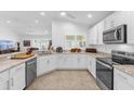 Well-lit kitchen with white cabinetry, stainless steel appliances, and a view into the living area at 10367 Addison Shore Way, Oxford, FL 34484