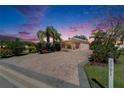 Charming home at sunset featuring a golf cart, brick driveway, manicured lawn and mature landscaping at 2991 Wood Duck Dr, Polk City, FL 33868