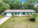 Attractive turquoise home featuring stone accents, a well-kept lawn, and a welcoming front entrance at 2690 Ne 42Nd Pl, Ocala, FL 34479