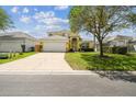 Inviting two-story home featuring a manicured lawn, mature tree, and a spacious driveway at 440 Langham Dr, Davenport, FL 33897