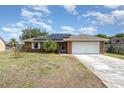 Charming single-story brick home featuring a two-car garage, solar panels, and green lawn at 820 Lamp Post Ln, Lakeland, FL 33809