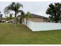 Exterior view of home featuring well-kept lawn, white fencing, and mature landscaping at 1500 Fort Meade Pl, Poinciana, FL 34759