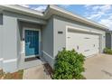 Inviting home exterior featuring a blue front door, a welcome sign, and a two-car garage at 1336 Madison Cir, Haines City, FL 33844