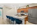 Modern kitchen featuring cherry wood cabinetry, an island with seating, and stainless steel appliances at 2055 Stake Out Way, Apopka, FL 32703