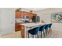 Modern kitchen featuring cherry wood cabinetry, an island with seating, and stainless steel appliances at 2055 Stake Out Way, Apopka, FL 32703