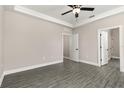 Spacious bedroom with crown molding, gray floors, ceiling fan, and multiple doorways at 7717 Somersworth Dr, Kissimmee, FL 34747