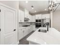 Modern kitchen features sleek white cabinets, stainless steel appliances, and a stylish quartz countertop island at 7756 Somersworth Dr, Kissimmee, FL 34747