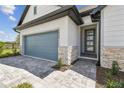 Close up on the home's exterior and gray garage door, showcasing stone and paved driveway at 16998 Cedar Valley Cir, Clermont, FL 34711
