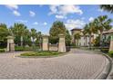 Gated community entrance with lush landscaping, decorative pillars, and a brick-paved roundabout at 1209 Payne Stewart Dr, Davenport, FL 33896