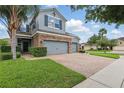 Stylish two-story home with a brick driveway, attached garages, and lush green lawn at 12243 Sawgrass Reserve Blvd, Orlando, FL 32824