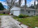View of the front of the gray brick home with a one car garage and cracked driveway at 4707 Melody Ln, Lakeland, FL 33805