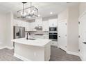 Modern white kitchen with stainless steel appliances, an island, and stylish lighting at 7733 Somersworth Dr, Kissimmee, FL 34747