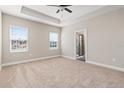Spacious bedroom featuring a tray ceiling, plush carpet, and access to the ensuite bathroom at 7733 Somersworth Dr, Kissimmee, FL 34747