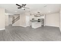 Open-concept living area featuring hardwood floors, a staircase, and a seamless transition into a modern kitchen at 7704 Somersworth Dr, Kissimmee, FL 34747
