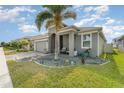 Single-story home boasts a lush lawn, vibrant landscaping, and a welcoming front porch with cozy seating at 140 Trinity Ridge Cir, Davenport, FL 33897