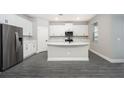 Modern kitchen with stainless steel refrigerator, white cabinets, and large center island at 3319 Chinotto Dr, Lake Alfred, FL 33850