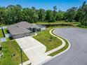 Aerial shot of a home featuring a spacious driveway, lush lawn, pond view, and three-car garage at 5419 Knights Landing Dr, Lakeland, FL 33810