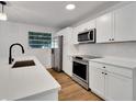 Modern kitchen with white cabinetry, stainless steel appliances, quartz countertops, and hardwood flooring at 800 N Church Ave, Mulberry, FL 33860