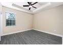 A spacious bedroom with tray ceiling, ceiling fan and a window to let in natural light at 7672 Somersworth Dr, Kissimmee, FL 34747