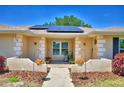 Inviting front porch with charming details, landscaping, hanging flowers, and solar panels on the roof at 53 Paine Dr, Winter Haven, FL 33884