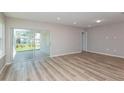 Open living room with light wood flooring and a sliding glass door to the outdoor patio at 6784 Sw 90Th Loop, Ocala, FL 34476