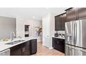 Stylish kitchen with stainless steel appliances, dark cabinets, white counters, and open layout to dining area at 4767 Waltham Forest Dr, Davenport, FL 33837