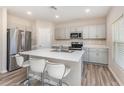 Modern kitchen features stainless steel appliances, stylish gray cabinets, a quartz countertop island, and barstool seating at 1646 Seth Dr, Winter Haven, FL 33880