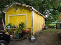 A backyard with a yellow storage shed, grill and propane tank, and gardening supplies at 730 Citrus St, Orlando, FL 32805