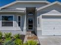 Inviting front entrance with mature landscaping, a Welcome mat, a garage, and a cheerful gray color scheme at 6229 Raven Run, Lakeland, FL 33809