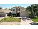 Charming two-story home featuring a stone facade, well-manicured landscaping, and a brick driveway at 1705 Plantation Pointe Dr, Orlando, FL 32824