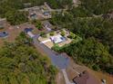 Aerial view of a home with a screened-in pool surrounded by lush trees in a serene neighborhood at 3690 Sw 175Th St, Ocala, FL 34473