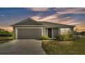 Charming single-story home with a two-car garage, neatly landscaped front yard, and neutral color palette at dusk at 513 Kimbrel Ct, Haines City, FL 33844