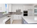 This bright kitchen features modern appliances, white cabinets, and a large island with a white countertop at 5844 Sw 87Th Ave, Ocala, FL 34481