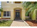 Inviting home entrance featuring an arched doorway, manicured landscaping, and a patterned walkway at 2523 Jasmine Trace Dr, Kissimmee, FL 34758