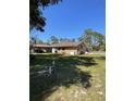 Expansive backyard featuring a brick home, a detached carport, and generous green space at 1275 Man O War Dr, Deland, FL 32724