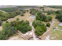 Aerial view of white house with gray roof and long driveway on expansive land with dense trees at 24025 Ranch Rd, Astatula, FL 34705