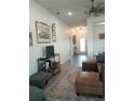 Spacious living room with wood-look tile flooring, leather furniture, TV, and access to the foyer at 4616 Grandview Glen Dr, Auburndale, FL 33823