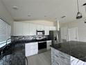 Bright kitchen showcasing white cabinetry, stainless steel appliances, and granite countertops at 1351 Pompay Dr, Davenport, FL 33896