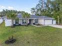 Inviting single-story home featuring a well-manicured lawn, palm trees, and an attached two-car garage at 6873 Sw 131St Pl, Ocala, FL 34473